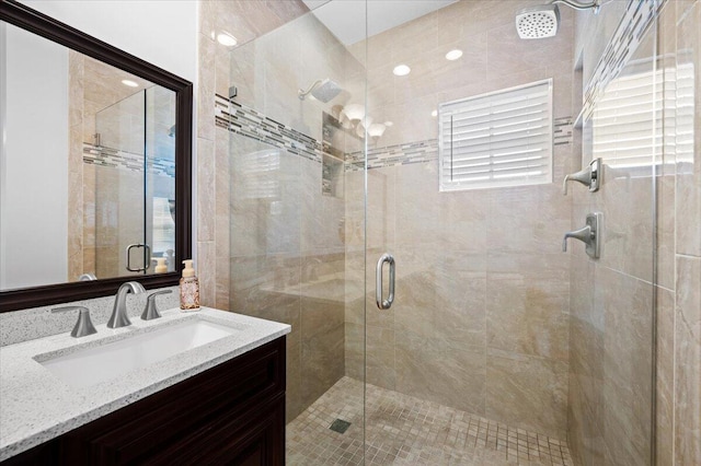 bathroom featuring vanity, a shower with shower door, and a wealth of natural light