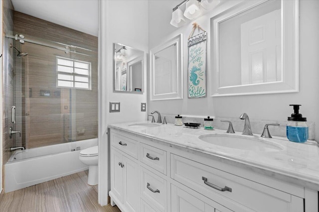 full bathroom with bath / shower combo with glass door, toilet, wood-type flooring, and vanity