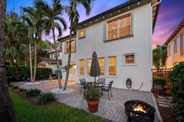 back house at dusk with an outdoor fire pit and a patio