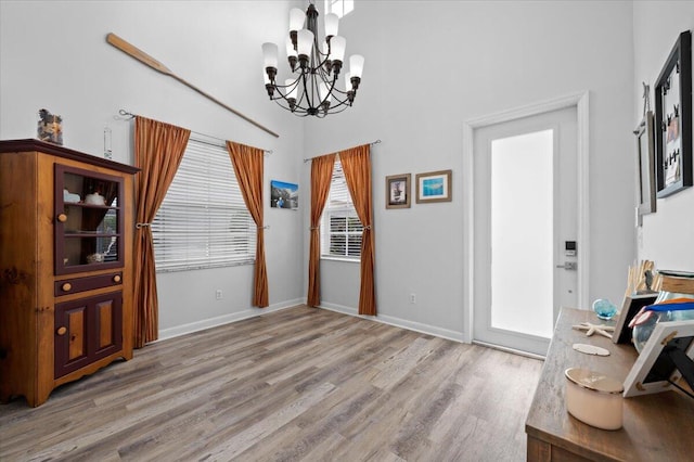 dining room with a notable chandelier, light wood-type flooring, and a high ceiling