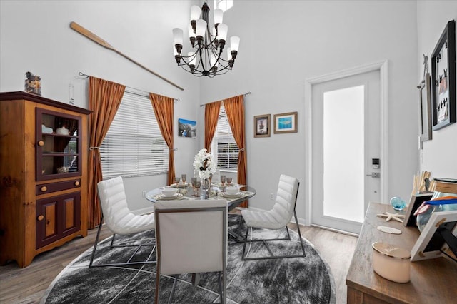 dining room with a towering ceiling, a chandelier, and dark hardwood / wood-style flooring