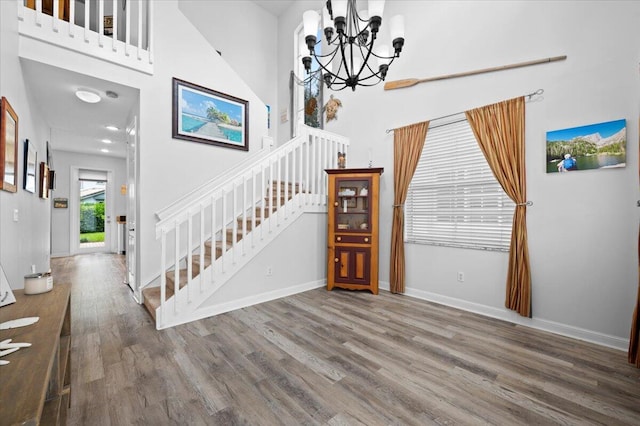 stairway with a towering ceiling, a notable chandelier, and hardwood / wood-style floors