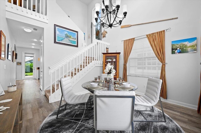 dining area featuring dark hardwood / wood-style floors, a high ceiling, and a chandelier