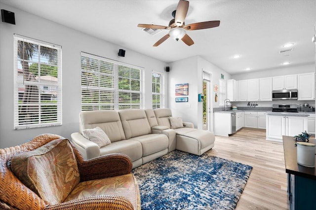 living room with sink, light hardwood / wood-style flooring, a wealth of natural light, and ceiling fan