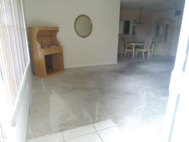 unfurnished living room with a chandelier and light colored carpet