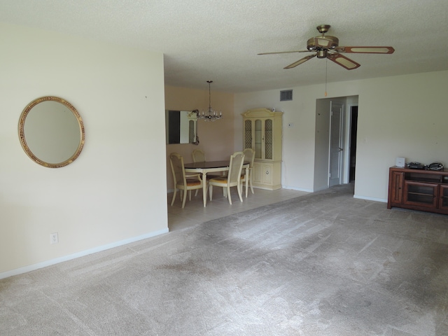 unfurnished living room featuring a textured ceiling, ceiling fan with notable chandelier, and carpet