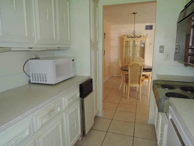 kitchen featuring hanging light fixtures, white cabinets, light tile patterned floors, a textured ceiling, and a chandelier