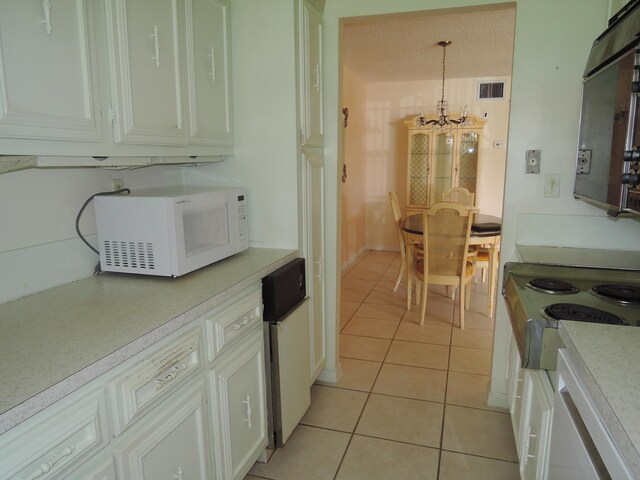 408 Sandpiper Dr Unit C, Fort Pierce, FL 34982 - kitchen with light countertops, white microwave, light tile patterned flooring, and a chandelier