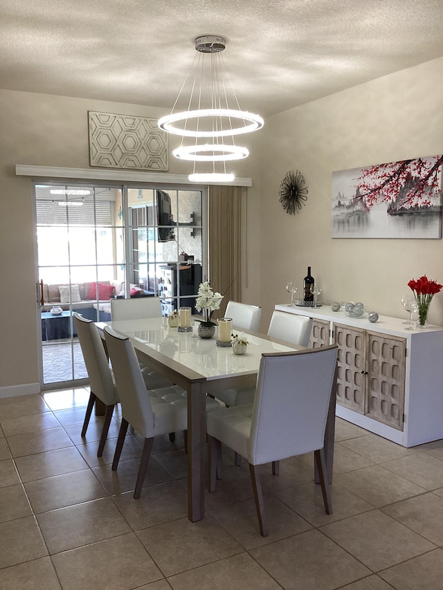 tiled dining room with a chandelier and a textured ceiling