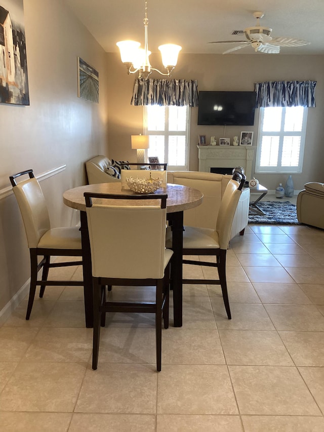 dining room with light tile patterned floors, ceiling fan with notable chandelier, and a wealth of natural light