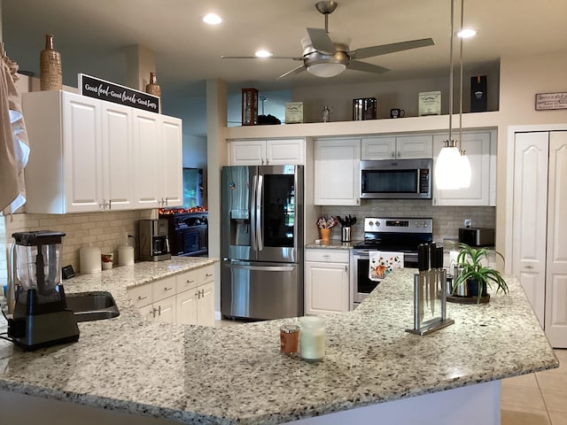 kitchen featuring light stone countertops, white cabinetry, stainless steel appliances, and decorative light fixtures