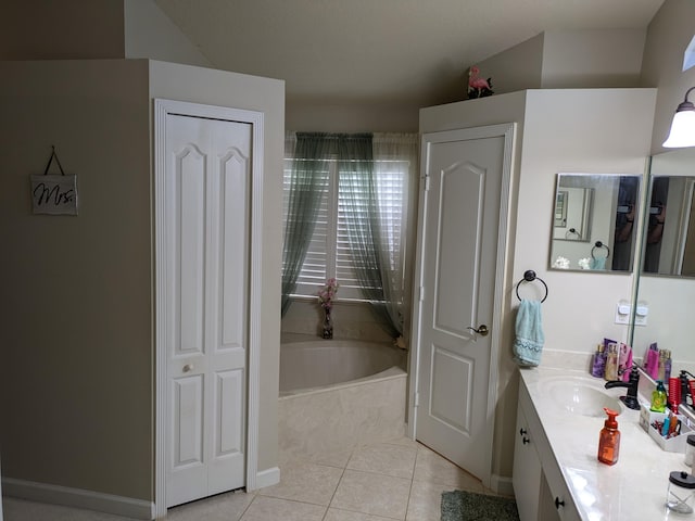 bathroom with tile patterned flooring, vanity, and tiled tub