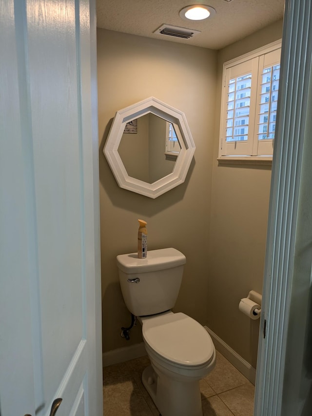 bathroom featuring tile patterned flooring, a textured ceiling, and toilet