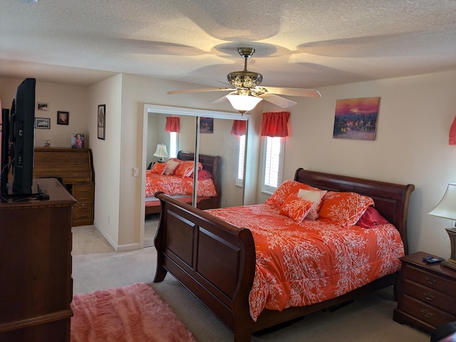 carpeted bedroom with ceiling fan, a textured ceiling, and a closet