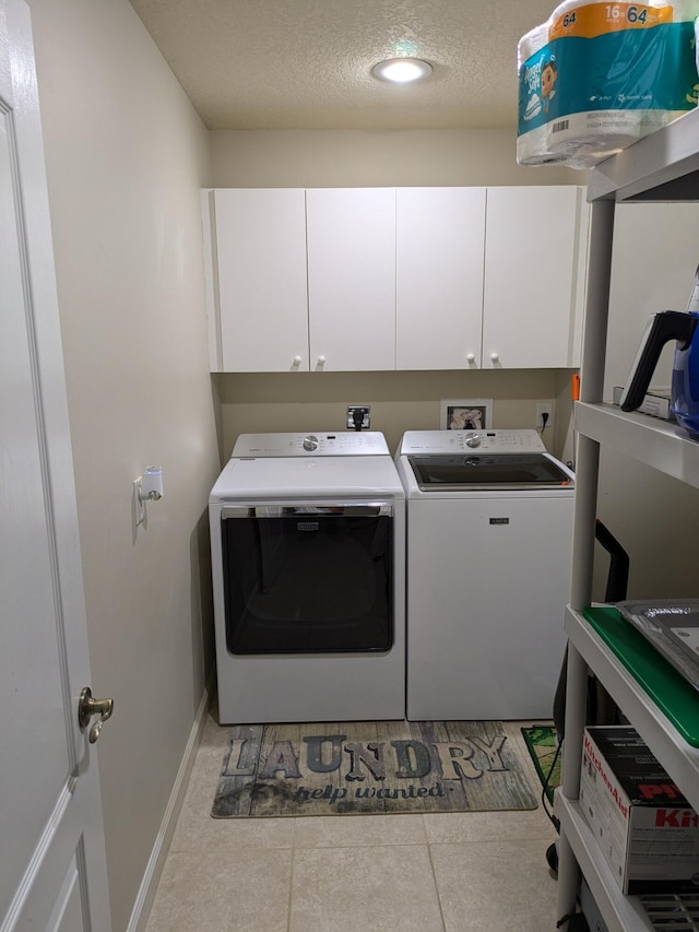 laundry area featuring cabinets, a textured ceiling, washing machine and dryer, and light tile patterned floors