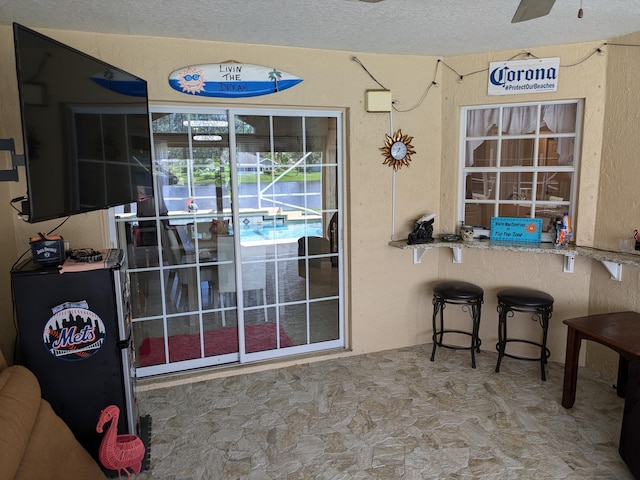 doorway with ceiling fan and a textured ceiling