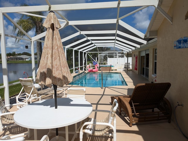 view of swimming pool featuring glass enclosure, a water view, and a patio