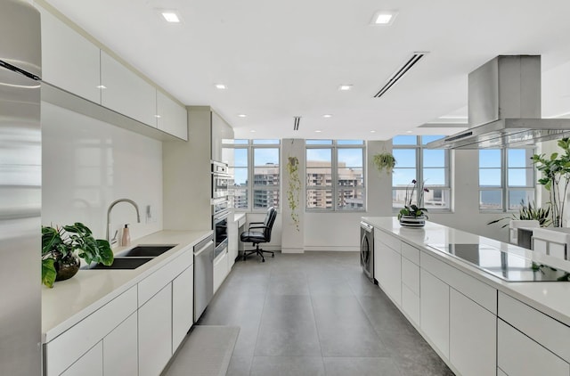 kitchen with modern cabinets, beverage cooler, island exhaust hood, a sink, and appliances with stainless steel finishes