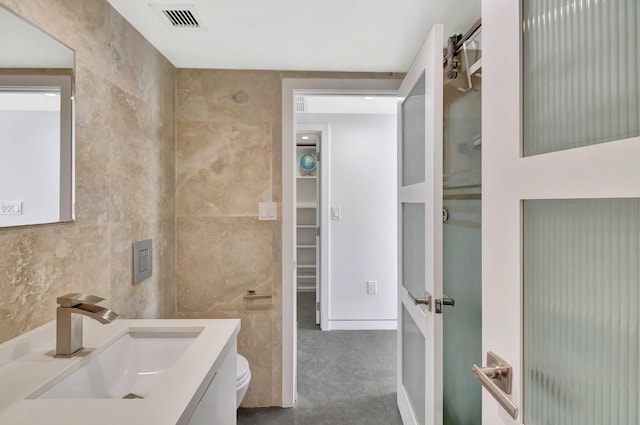 bathroom featuring visible vents, toilet, tile walls, and vanity