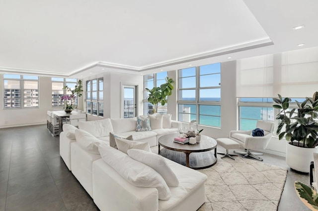 living room featuring a raised ceiling, recessed lighting, and a wealth of natural light