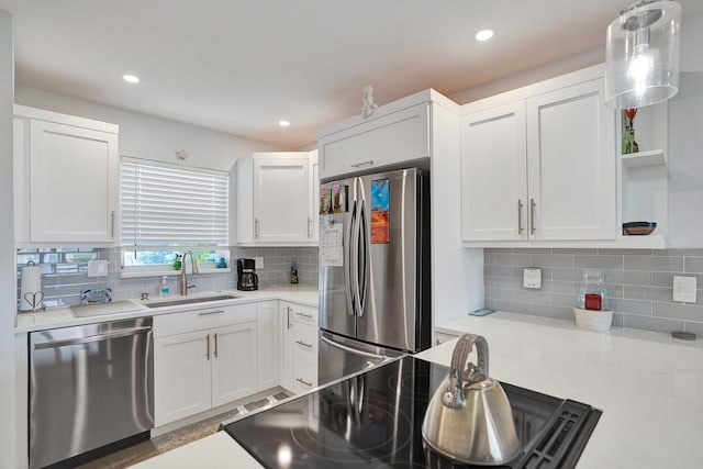 kitchen featuring white cabinets, pendant lighting, sink, backsplash, and stainless steel appliances