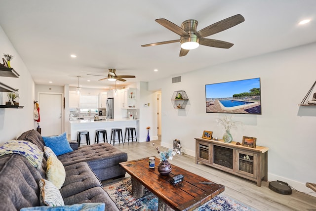 living room with light hardwood / wood-style floors and ceiling fan