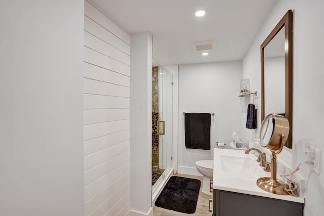 bathroom with hardwood / wood-style flooring, walk in shower, vanity, and toilet