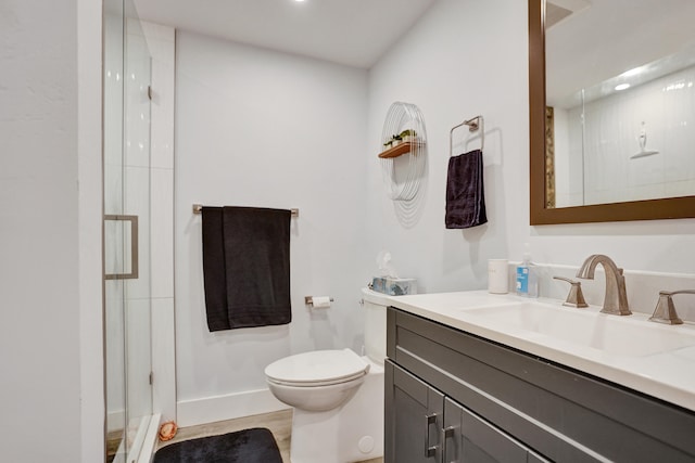 bathroom featuring vanity, a shower with shower door, and toilet