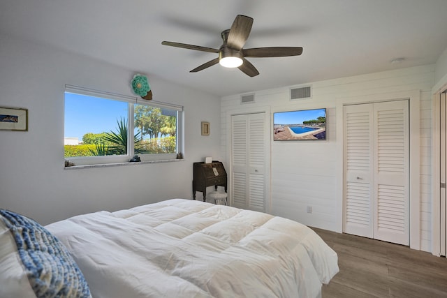 bedroom featuring two closets, ceiling fan, and hardwood / wood-style floors