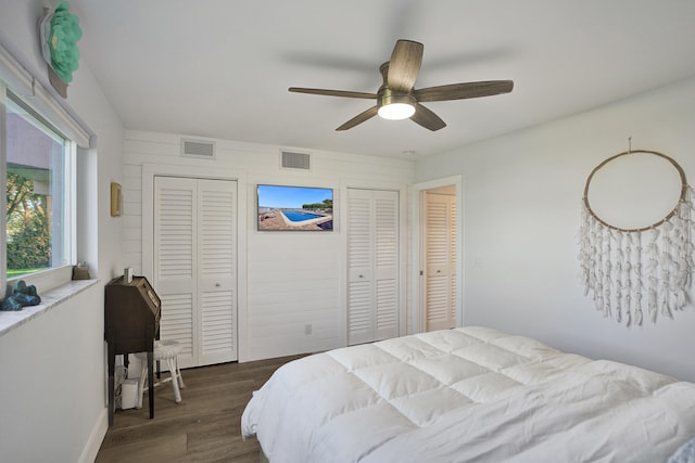 bedroom with two closets, ceiling fan, and dark hardwood / wood-style flooring