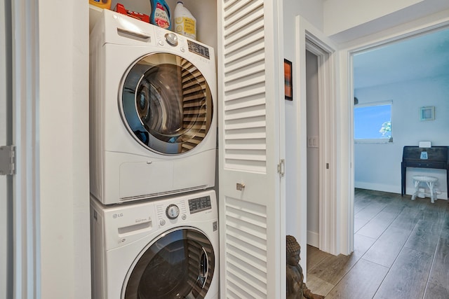 clothes washing area featuring stacked washer and dryer and dark hardwood / wood-style flooring