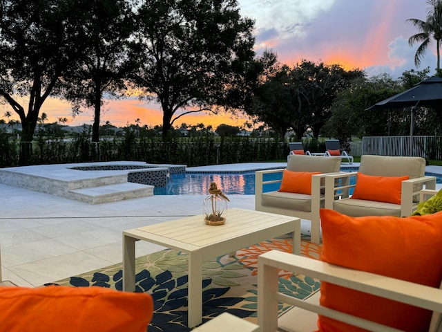 pool at dusk featuring a patio and an in ground hot tub