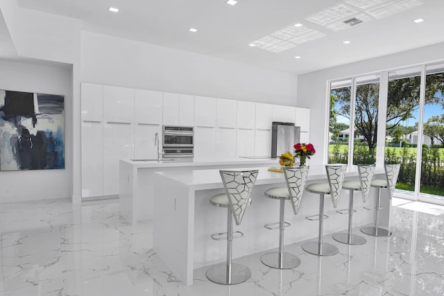 kitchen featuring white cabinets, a breakfast bar area, stainless steel appliances, and a kitchen island