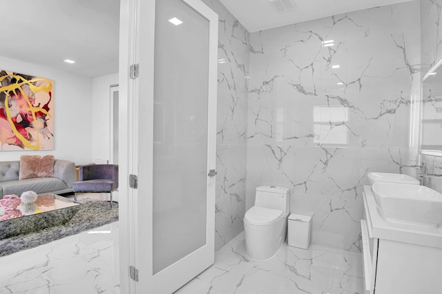 bathroom with vanity, tile walls, and toilet