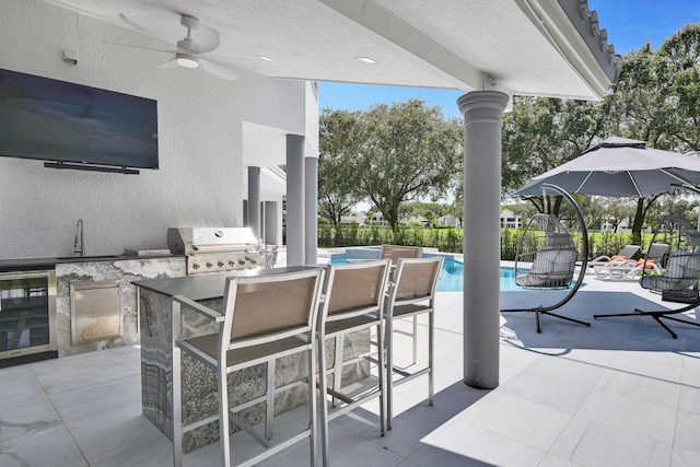 view of patio / terrace featuring ceiling fan, area for grilling, sink, beverage cooler, and exterior kitchen