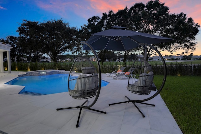 pool at dusk featuring a patio, an in ground hot tub, and a yard