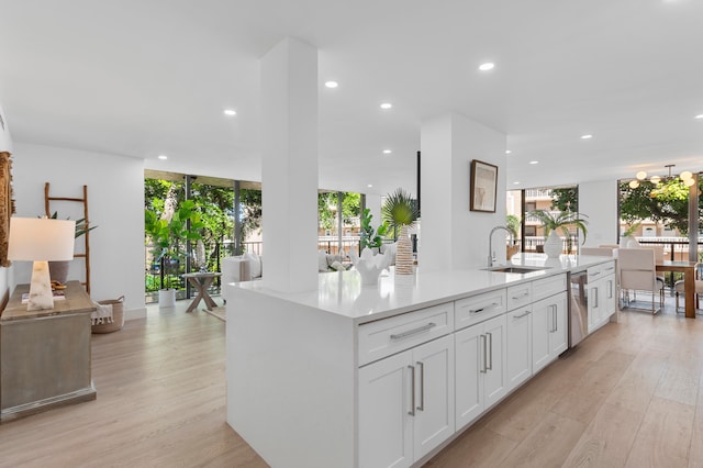 kitchen featuring an island with sink, white cabinets, light hardwood / wood-style flooring, stainless steel dishwasher, and sink