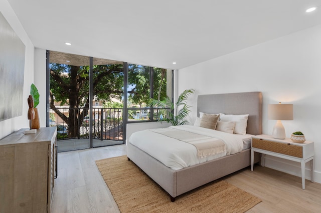 bedroom featuring light wood-type flooring, access to exterior, and expansive windows