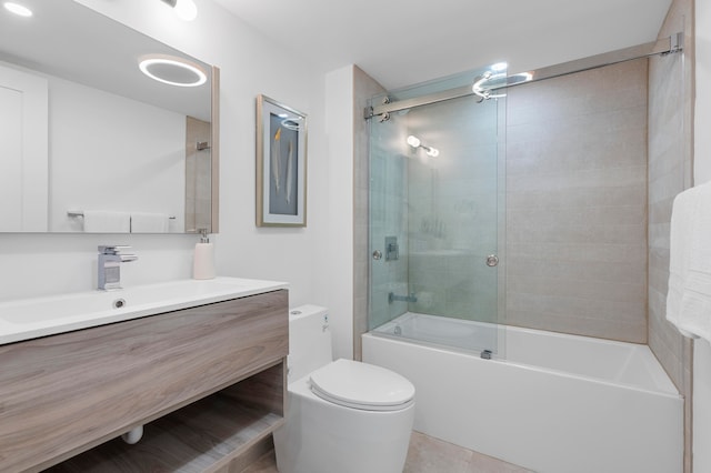 full bathroom featuring bath / shower combo with glass door, vanity, tile patterned flooring, and toilet