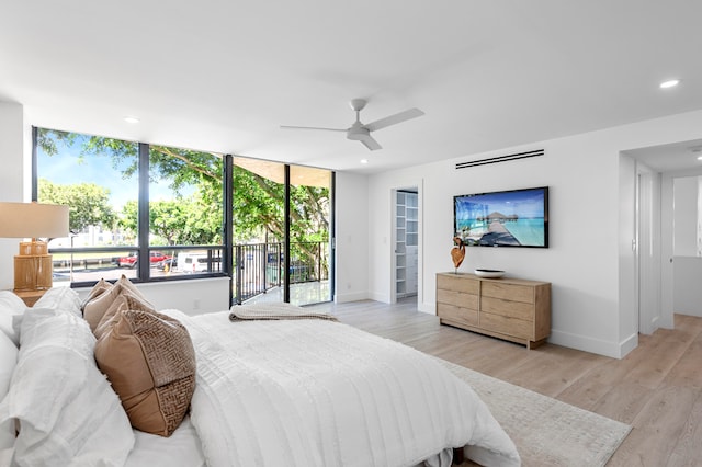 bedroom with light wood-type flooring, floor to ceiling windows, ceiling fan, and access to exterior