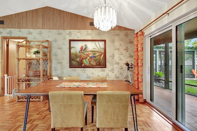 dining space with light parquet floors, a chandelier, and vaulted ceiling