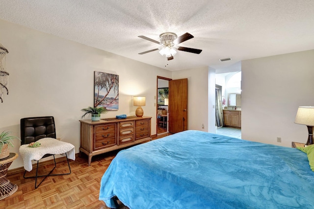 bedroom featuring a textured ceiling, ensuite bathroom, light parquet floors, and ceiling fan