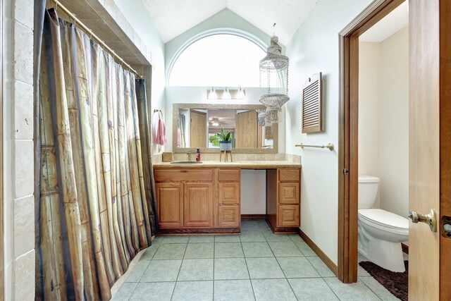 bathroom featuring tile patterned floors, vanity, toilet, and lofted ceiling