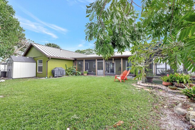 rear view of property with a sunroom, a shed, and a lawn