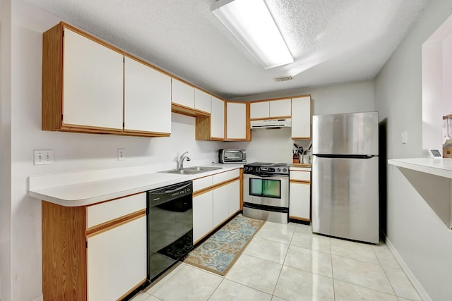 kitchen with sink, white cabinetry, light tile patterned floors, appliances with stainless steel finishes, and a textured ceiling