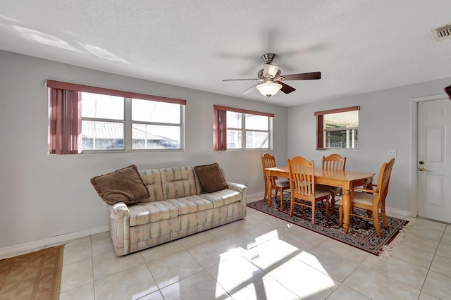 tiled dining room with ceiling fan and a textured ceiling