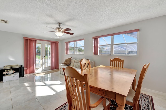 tiled dining area with french doors, a textured ceiling, and ceiling fan