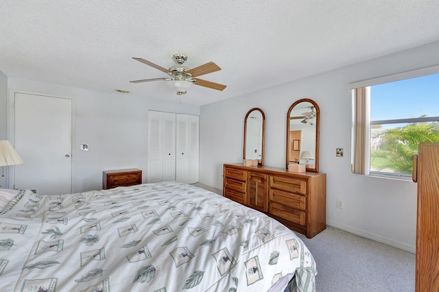 bedroom featuring light carpet, a textured ceiling, and ceiling fan