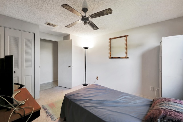 carpeted bedroom with a textured ceiling, a closet, and ceiling fan