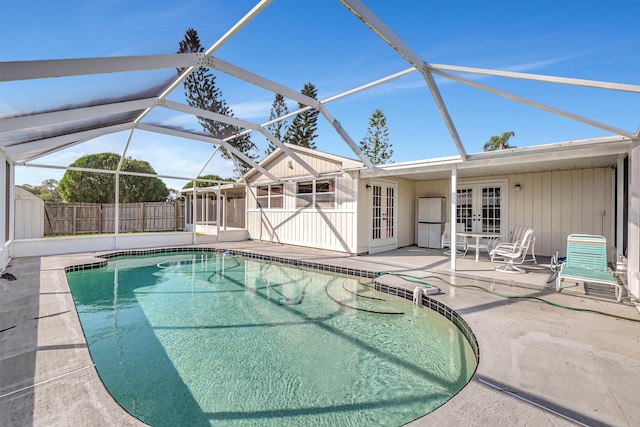 view of swimming pool featuring an outbuilding, french doors, a patio, and a lanai